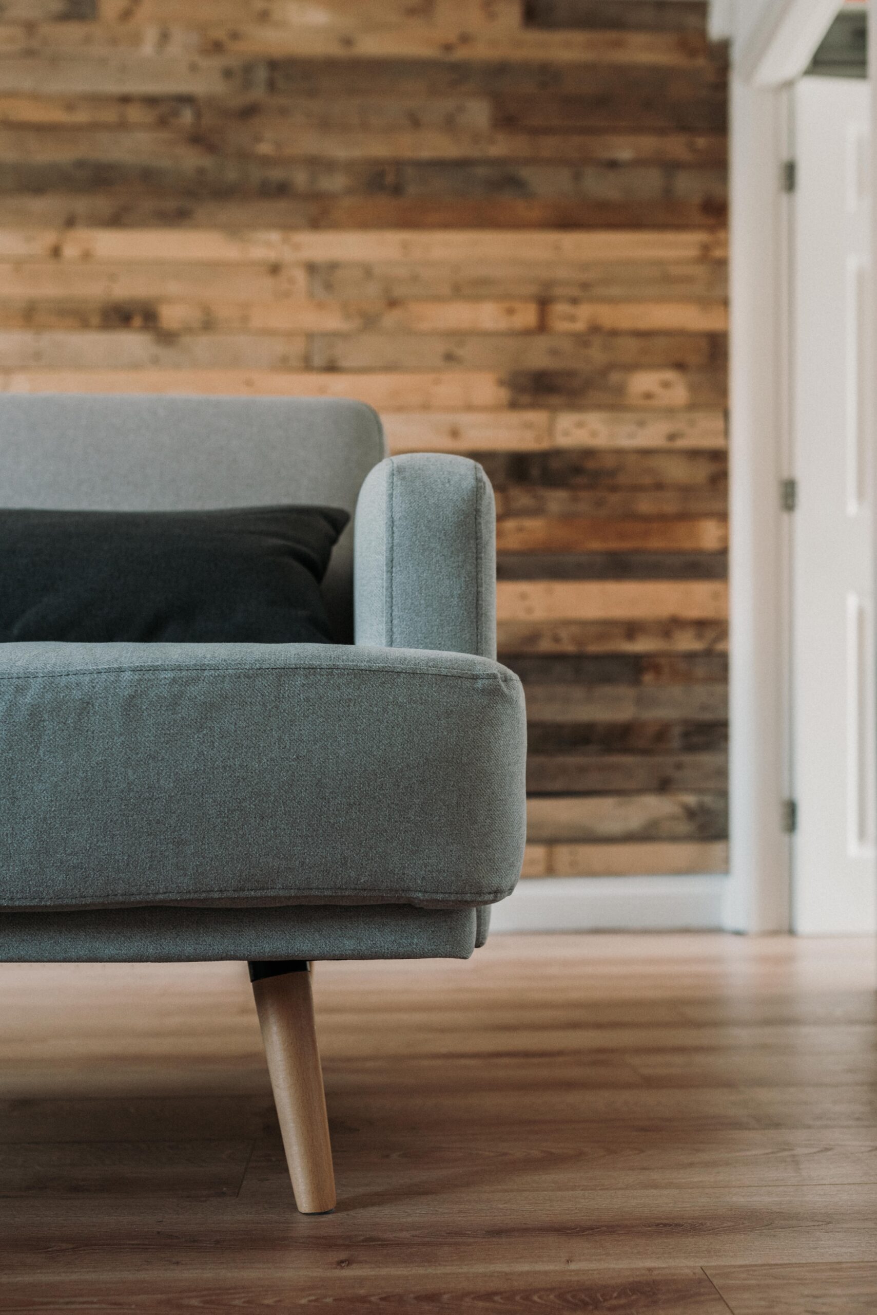 Vertical close up half shot of a gray sofa with a black pillow on it